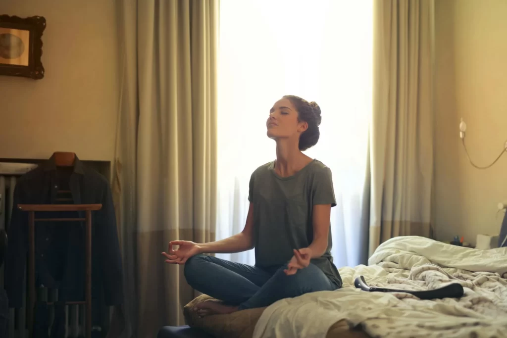 Eine Frau, die auf dem Boden ihrer Wohnung meditiert, um Stress abzubauen